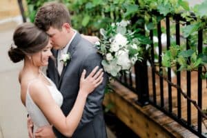 Bride and groom hugging next to patio with vines
