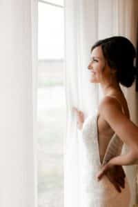 Young women in wedding gown looking out the window