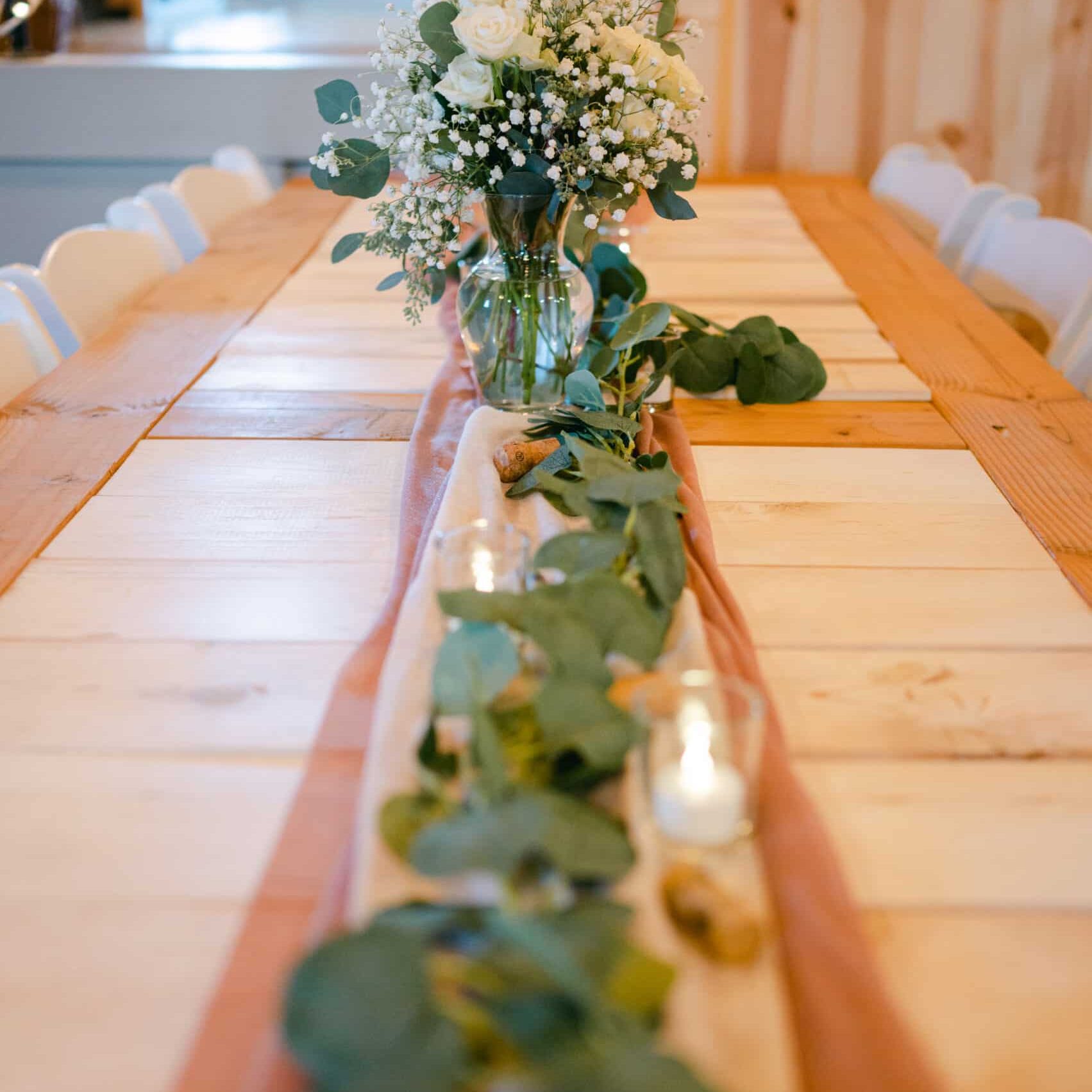 Reception table with white and green floral table runners and candles